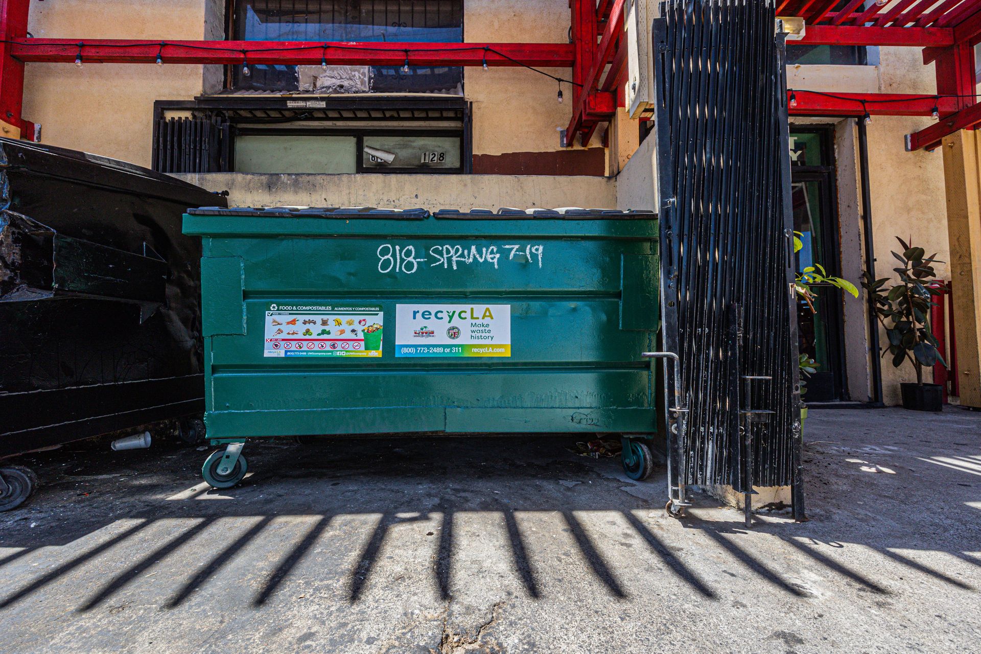 Front view of a green dumpster outside an urban building under daylight.
